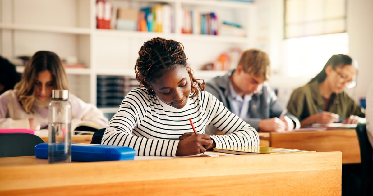 High school students writing essay in classroom for assessment