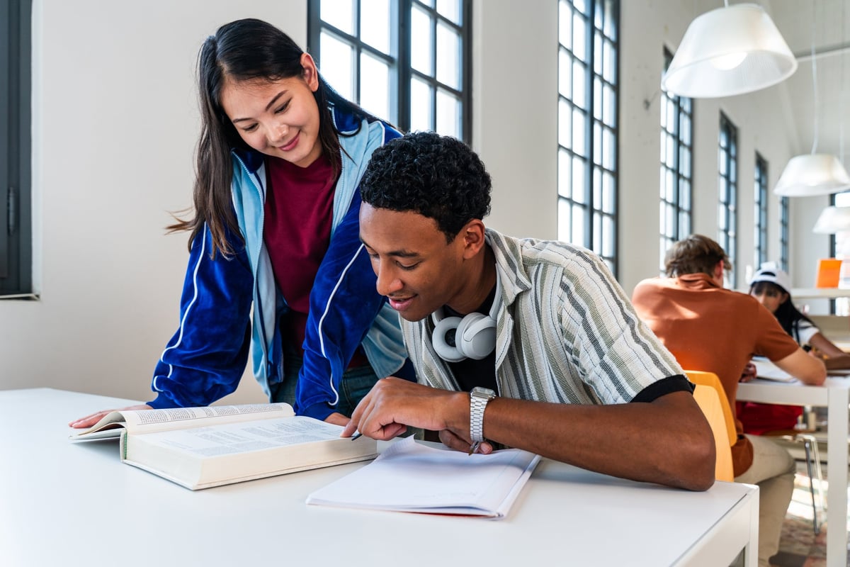 Multiethnic group of young students working together on a project at a library table